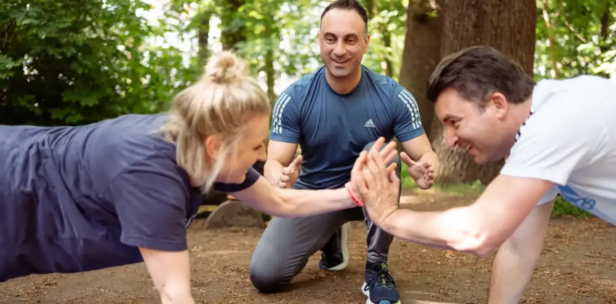 Drei Personen geben sich beim Training im Wald ein High-Five
