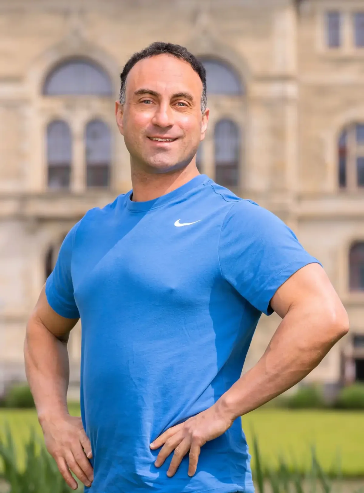 Ich, Nico Fichtler, Personal Trainer aus Hannover, stehe lächelnd vor einem historischen Gebäude